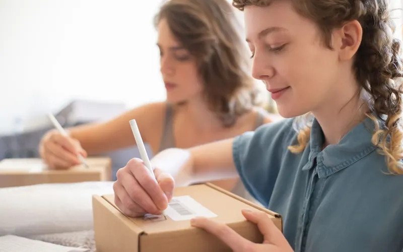 Dos personas etiquetan cajas de pedidos para enviar